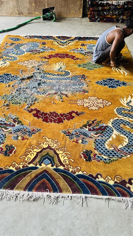 A hand-tufted rug being carved by hand with long-blade shears to the design&rsquo;s raised relief