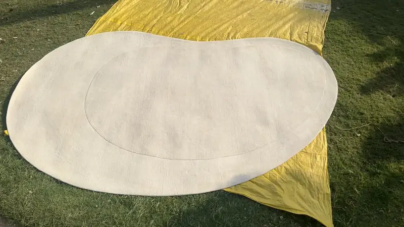 A custom-shaped rug drying flat after washing, held under tension to true its edges