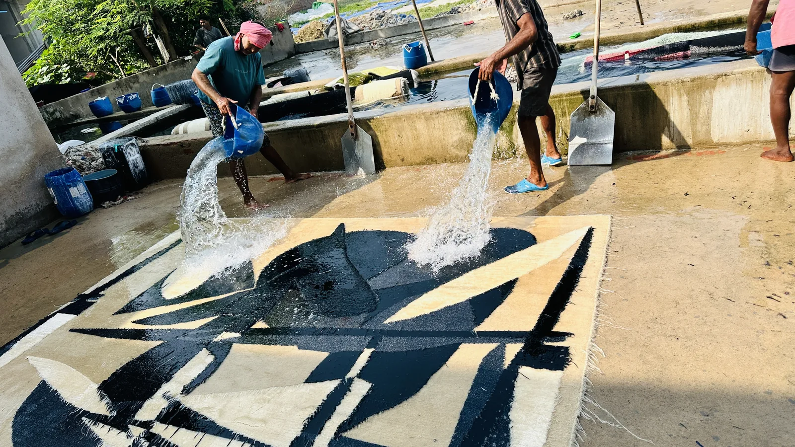 A hand-knotted rug being washed on the finishing floor at PiHue, Bhadohi