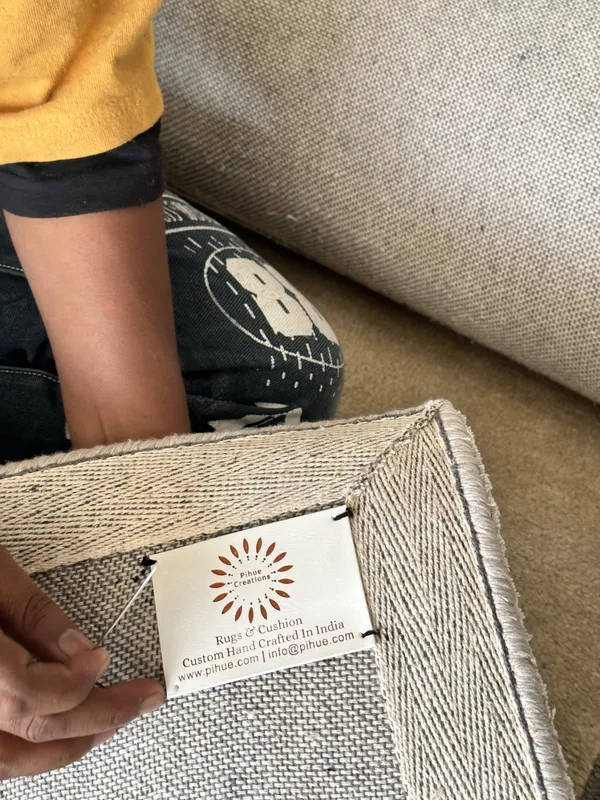 A woven label being hand-sewn onto the reverse of a flatweave